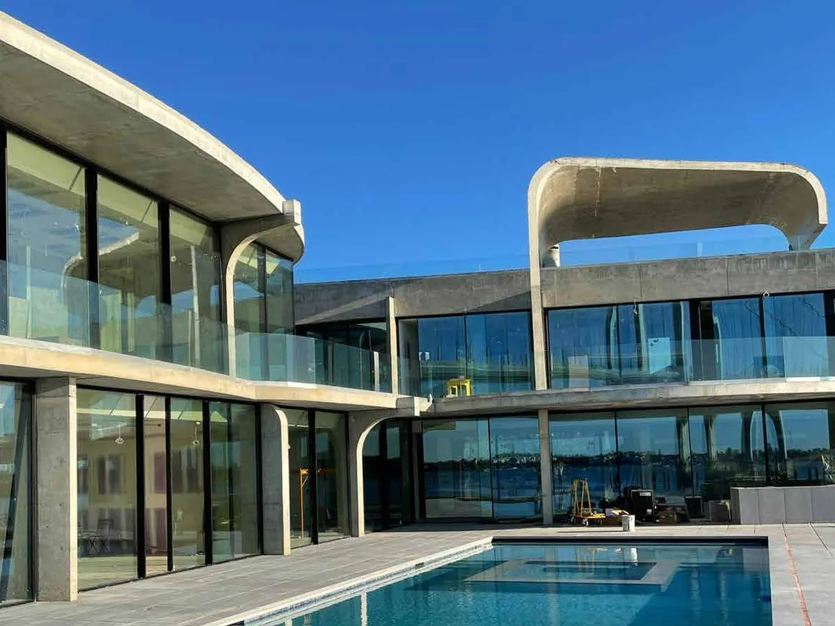Poolside pavilion enclosed by wide glazed panels in slim dark frames spanning the full elevation.