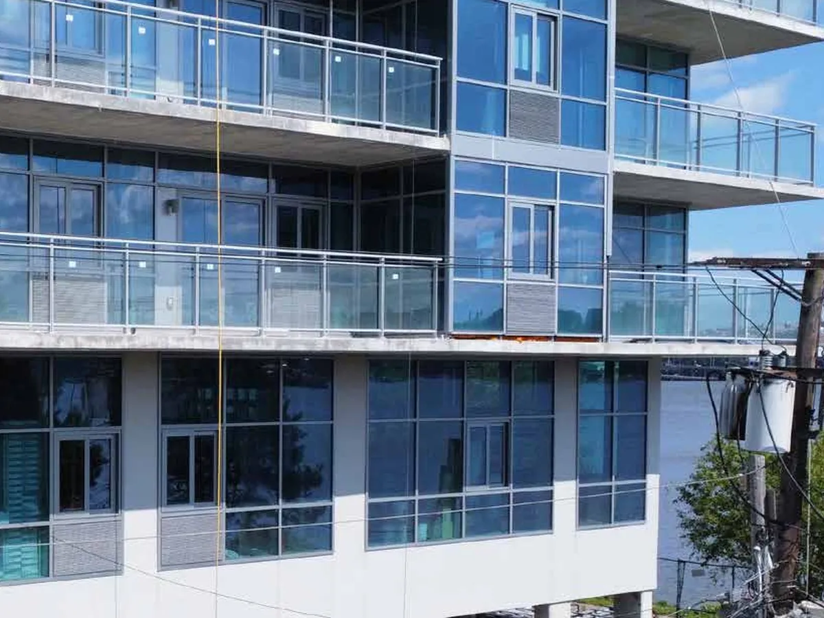 Apartment balconies fronted by clear glass railing panels held in slim metal top rails.