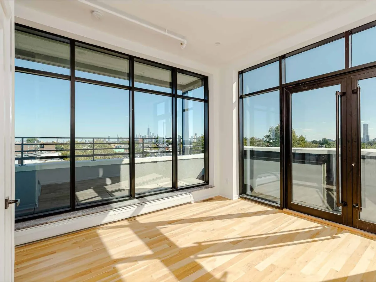 Corner room with large sliding glazed panels in dark aluminum frames opening onto a terrace.