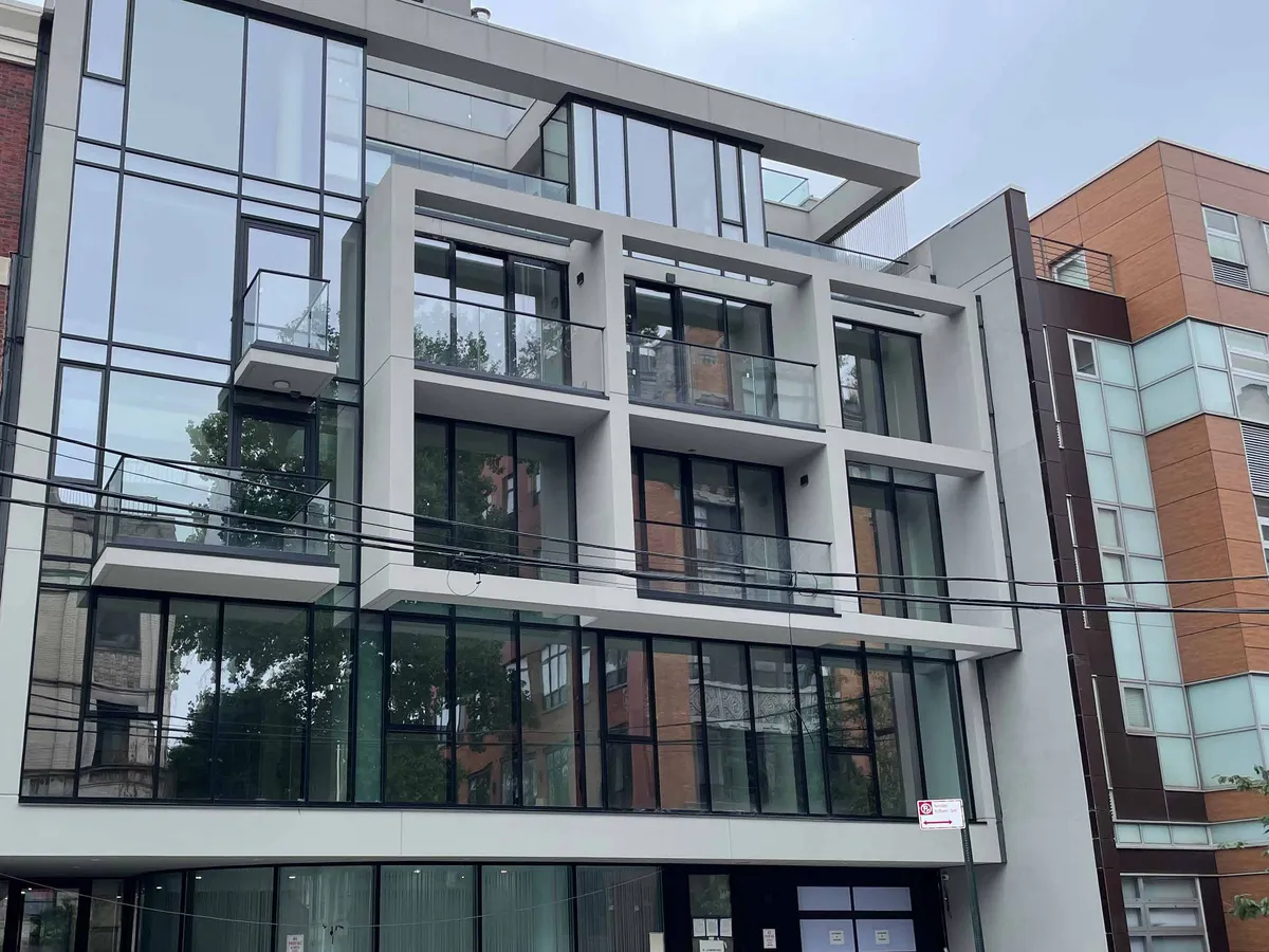 Multi-storey residential building with floor-by-floor window-wall glazing set between white slab edges.