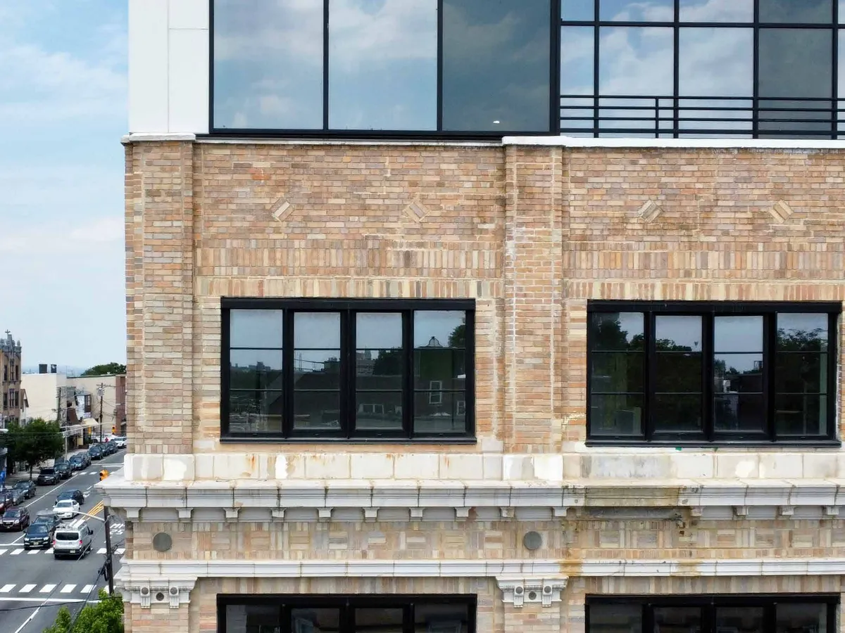 Close view of large dark aluminum-framed windows set into a masonry wall above a street.